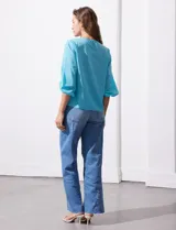 Blusa de gasa con estampado geométrico en tonos negro, gris y celeste. Tiene cuello redondo y mangas 3/4 amplias con abertura y botón.