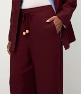Pantalón de corte recto confeccionado en mezcla de viscosa y lino. Presenta cintura elástica con cordón ajustable y bolsillos laterales.