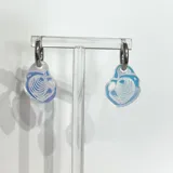 Aros colgantes con forma de ostra, con base transparente y dibujo de líneas blancas.