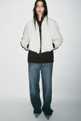 Chaqueta estilo bomber de cuello solapa y manga larga, confeccionada en material efecto piel color beige. Presenta cierre frontal con cremallera, bolsillos delanteros de vivo y bajo con acabado elástico.