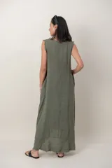 Vestido largo de lino color verde militar, sin mangas, con cuello redondo y bolsillos laterales. Presenta detalles desflecados en las sisas y en el dobladillo asimétrico.
