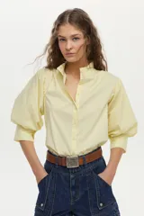 Camisa amarilla de mangas abullonadas, con cuello mao y voladito. Confeccionada en mezcla de algodón, poliamida y elastano.