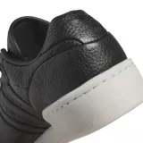 Championes adidas Rivalry Lux Low de cuero negro con textura granulada, diseño de caña baja y suela de plataforma en color blanco hueso.