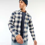 Camisa de manga larga con estampado de cuadros en tonos azul y beige, confeccionada en tejido de algodón con cierre frontal de botones.