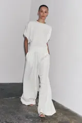 Pantalón palazzo color blanco, confeccionado en tejido de lyocell, de tiro medio, cintura elástica ajustable con cordones, bolsillos laterales ocultos y pierna ancha.