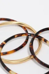 Pulsera rígida combinada de acetato con estampado carey y aros metálicos en tono dorado mate.