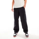 Pantalón negro de algodón con bolsillos tipo cargo y logo de Nike bordado en el muslo. Corte relajado.