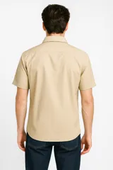 Camisa color beige de algodón con botones y cuello camisero, de manga corta y corte clásico.