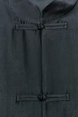 Camisa de estilo oriental confeccionada en mezcla de lyocell con acabado satinado. Presenta cuello redondo, manga larga con puños rectos, bolsillos de plastrón y cierre frontal mediante alamares.