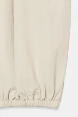 Pantalón de tiro medio y cintura elástica con cordón de ajuste, bolsillos laterales y bajo abullonado con puños elásticos. Confeccionado en poliamida.