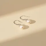 Caravanas colgantes de plata 925 con perlas de río en forma de gota y detalle de engaste con circonias en la parte superior.