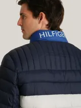 Chaqueta acolchada de diseño color block en tonos azul marino, blanco y azul brillante. Presenta cuello alto, cierre frontal con cremallera y bolsillos laterales con cierre. Incluye el logo de la marca bordado en el pecho y detalle distintivo en la manga.
