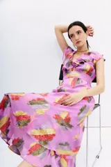 Vestido midi sin mangas, color lila, con escote en V adornado con volados y cinturón a tono. Presenta un estampado floral en jacquard de lurex multicolor con tonos rojos, amarillos y plateados.