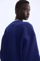 Buzo de tejido de punto color azul marino, con cuello redondo y diseño de texto universitario en el pecho que dice "MILANO ATHLETICS".