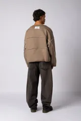 Buzo oversize de corte boxy, confeccionado en algodón rústico de alto gramaje en color beige. Presenta cuello redondo con borde crudo, mangas largas y una estampa frontal con el texto VCP delimitado por líneas horizontales blancas.