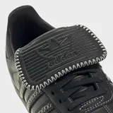 Championes Adidas Samba LT de cuero negro con las tres tiras laterales en blanco y suela de goma color caramelo.