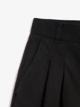 Pantalón negro de corte ancho, con pinzas en la cintura y bolsillos laterales.