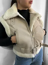 Chaleco color beige con interior de piel sintética blanca, cierre frontal con cremallera y cinturón ajustable en la cintura.