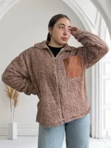 Campera de abrigo tipo teddy color camel, con cierre frontal y bolsillo de cuero sintético en el pecho.