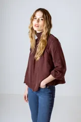 Blusa negra de manga larga con cuello alto fruncido y diseño amplio con frunces en la parte superior.