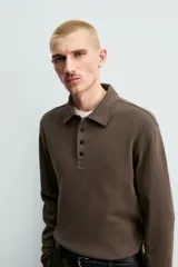 Polo de manga larga con corte regular fit, confeccionado en tejido de algodón con acabado cepillado. Presenta cuello solapa y cierre frontal con botonadura.