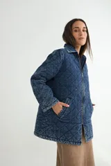 Chaqueta de denim azul con diseño acolchado en forma de rombos, cierre frontal con cremallera y bolsillos laterales.