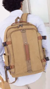 Mochila de tela canvas color beige con detalles en símil cuero marrón. Tiene presillas y broches plásticos para ajustar, bolsillo frontal con cierre, repartición interna para laptop, bolsillos laterales, correas cortas para usar como bolso de mano y correas regulables para la espalda.