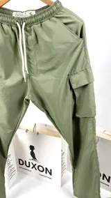 Pantalón cargo verde de nylon, corte holgado con bolsillos laterales y cintura elástica ajustable con cordón.