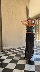 Falda larga negra de tejido red calada con lurex dorado, pretina elástica y tajos laterales. Incluye forro en la zona del caderín.