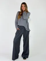Pantalon de vestir de corte sastrero y pierna ancha, color gris oscuro, con pinzas frontales y bolsillos laterales.