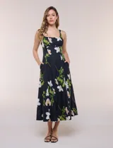 Vestido midi evasé de algodón color negro con estampado floral blanco y verde, de la marca Julia Jordan. Presenta escote recto, breteles anchos y espalda en punto smock. Incluye bolsillos laterales y forro interior de poliéster.