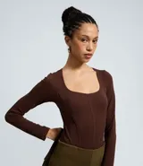 Body manga larga de poliamida con diseño seamless y escote cuadrado. Presenta costuras verticales frontales que simulan un corte tipo corset y cierre con botones de presión en la entrepierna.