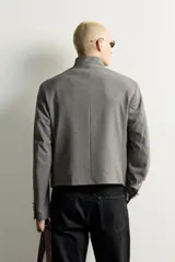 Blazer cropped de corte ajustado con estampado de cuadros, cuello mao y manga larga. Cuenta con bolsillos con solapa en la cadera y cierre frontal de botones.