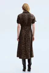 Vestido midi con estampado de leopardo, cuello camisero, botones frontales y mangas cortas con detalle de lazos. Cuenta con una costura fruncida con cinturón para atar en la cintura y falda con leve vuelo.
