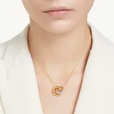 Colgante dorado con dos aros entrelazados, uno de ellos con pavé de cristales blancos. La cadena tiene un cristal Swarovski en el extremo.