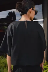 Top de lino con cuello redondo y manga corta. Presenta dos bolsillos frontales, bajo ajustable con cordones y cierre en la espalda con abertura y botón.