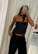 Top tejido color beige con lurex, de breteles finos y escote halter cruzado con abertura central.