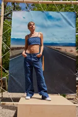 Pantalón de jean azul denim con tiro bajo, corte oversize y grabado láser con monograma.