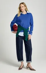 Sweater de punto color azul, de corte recto y ligero estilo holgado, con cuello redondo, mangas largas con puños ajustados por botones metálicos y dobladillo acanalado.