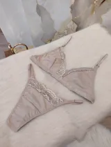 Conjunto de lencería compuesto por un corpiño triangular y una bombacha tipo colaless, ambos confeccionados en algodón color nude con delicados detalles de encaje en los bordes.