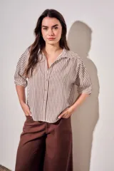 Camisa de corte oversize con estampado de rayas verticales en tonos marrón y beige. Presenta cuello camisero, cierre frontal con botones y mangas cortas con caída relajada.
