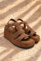 Sandalias de gamuza color marrón tostado, con plataforma corrida, tiras anchas entrecruzadas y tira ajustable con hebilla en el tobillo.
