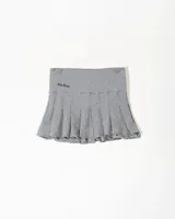 Minifalda tableada de tiro bajo con estampado de cuadrillé en blanco y negro. Presenta un pequeño bordado decorativo en el frente.