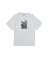 Remera de manga corta color blanco con estampa fotográfica central en blanco y negro que muestra un edificio con un cartel publicitario y el logo de la marca en rojo.