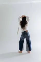 Jean de corte oxford con tiro medio-alto, confeccionado en algodón. Presenta un diseño de paneles con cortes verticales en dos tonos de azul y costuras marcadas en las piernas, ofreciendo una silueta amplia y fluida.