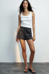 Musculosa de algodón blanca con escote redondo y el texto 'BETTER IN IBIZA' estampado en negro en el centro del pecho.