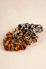 Set de tres gomitas de pelo tipo scrunchie con estampado animal print en tonos marrón, beige y negro.