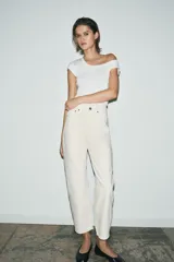 Jeans de tiro medio con corte tapered, confeccionados en denim de color negro con costuras en contraste. Presentan diseño de cinco bolsillos, trabillas en la cintura y cierre frontal con cremallera y botón.