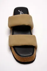 Sandalias planas Free People modelo Fairmount Flared, con plataforma de corcho acampanada, plantilla negra y dos tiras acolchadas anchas de cuero color beige.