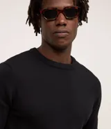 Suéter masculino de tejido de punto pesado, color negro, con cuello redondo y mangas largas con puños acanalados. Presenta un diseño liso con barra ajustada en la cintura.